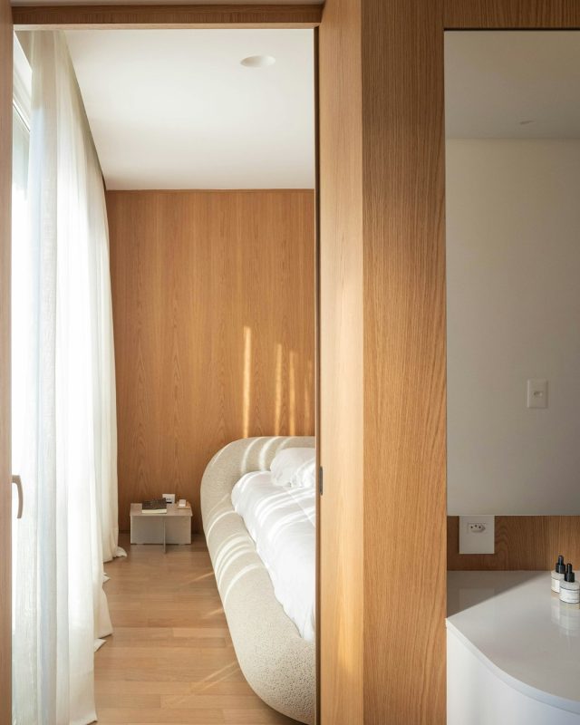 A wooden doorway leads to a stylish, modern bedroom