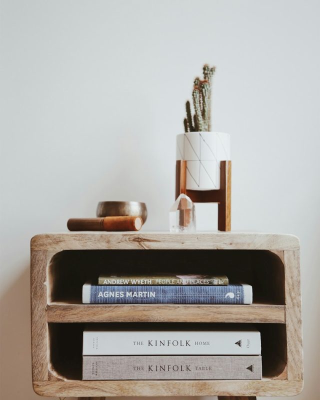 books in brown wooden side table beside white wall